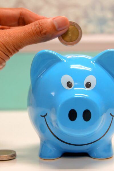 person putting coin in a piggy bank